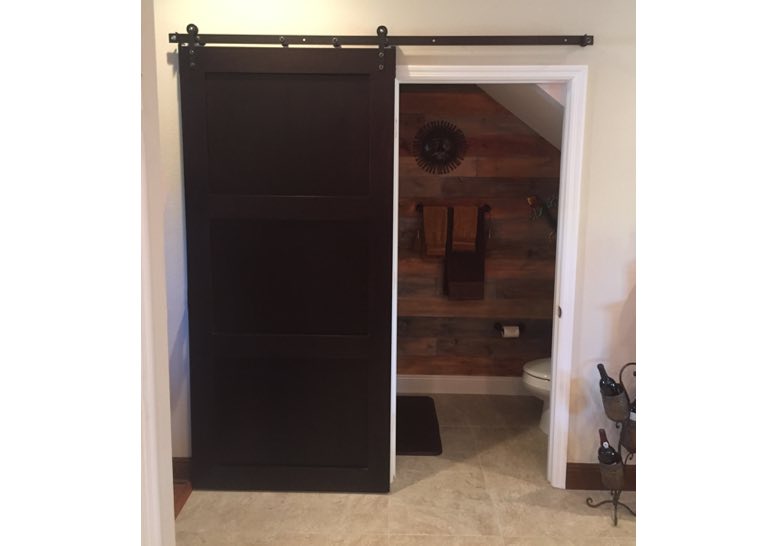 Brown sliding barn door covering bathroom entry 